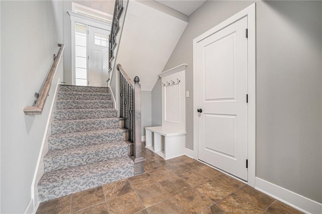 staircase featuring stone finish floor and baseboards