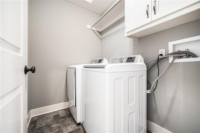 washroom featuring independent washer and dryer, baseboards, stone finish flooring, and cabinet space