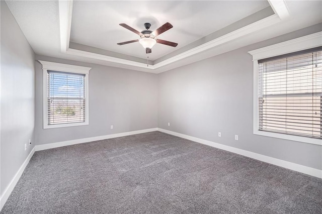 carpeted empty room with a tray ceiling, baseboards, and a ceiling fan