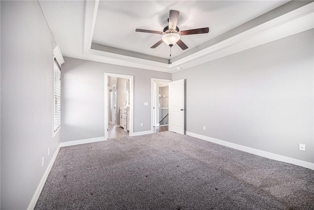 unfurnished bedroom with a raised ceiling, ceiling fan, carpet flooring, and baseboards