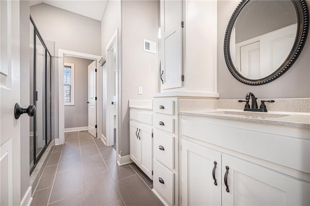 bathroom featuring vanity, visible vents, baseboards, and a stall shower