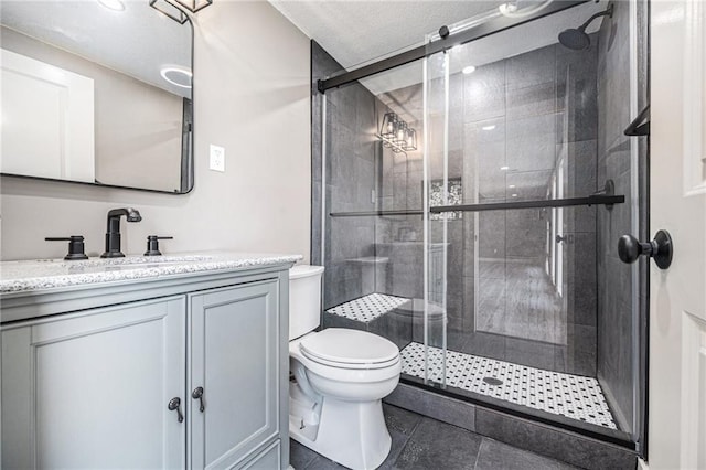 bathroom with a shower stall, tile patterned flooring, vanity, and toilet