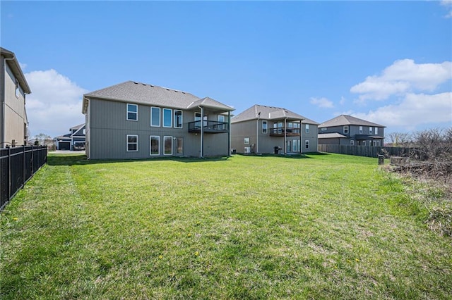back of house featuring a yard, fence, and a balcony