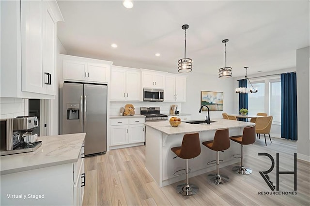 19703 W 196th St, Spring Hill, KS 66083 - kitchen with appliances with stainless steel finishes, tasteful backsplash, light wood-style flooring, a kitchen breakfast bar, and white cabinets
