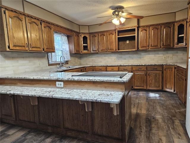 415 N Western St, Girard, KS 66762 - kitchen featuring a peninsula, dark wood-style floors, a kitchen bar, brown cabinets, and a sink