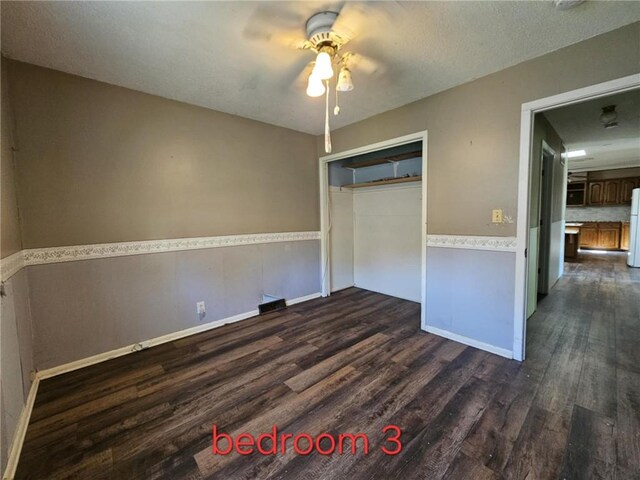 415 N Western St, Girard, KS 66762 - unfurnished bedroom featuring ceiling fan, dark wood-type flooring, a closet, a wainscoted wall, and baseboards