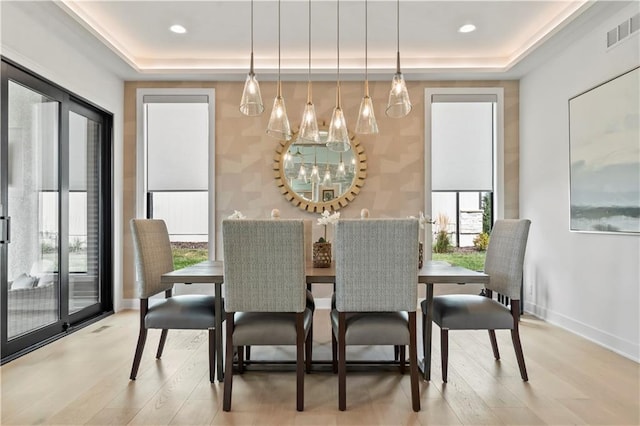 dining space featuring a tray ceiling, wood finished floors, a notable chandelier, and visible vents