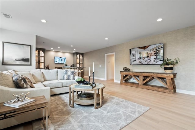 living room with recessed lighting, visible vents, baseboards, and wood finished floors
