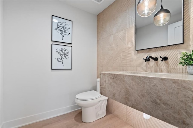 bathroom with a sink, toilet, wood finished floors, and baseboards