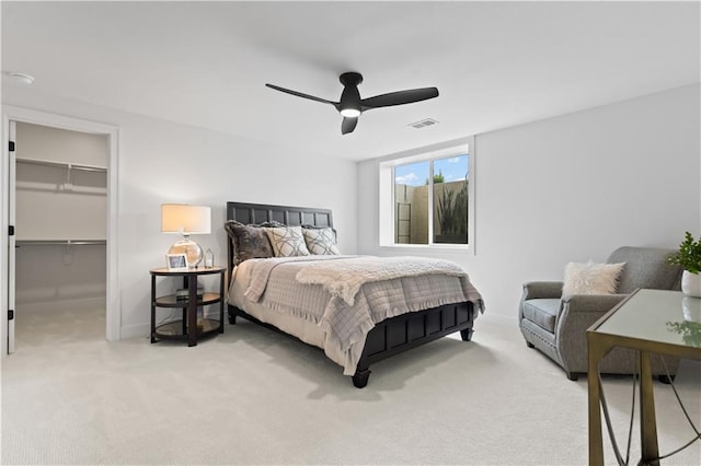 carpeted bedroom featuring a closet, baseboards, a ceiling fan, a walk in closet, and visible vents