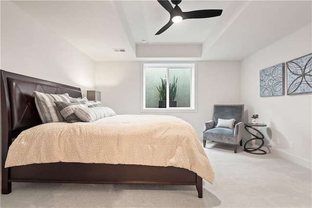 carpeted bedroom with a raised ceiling, ceiling fan, baseboards, and visible vents