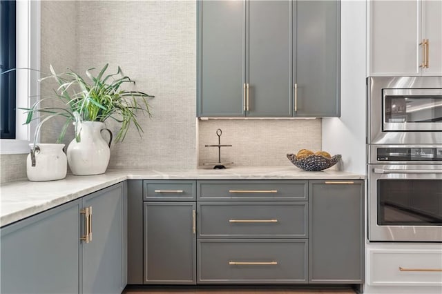4506 W 136th Ter, Leawood, KS 66224 - kitchen featuring stainless steel appliances, gray cabinetry, tasteful backsplash, and light stone counters