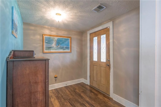 foyer entrance featuring a textured ceiling, baseboards, dark wood-style floors, and visible vents