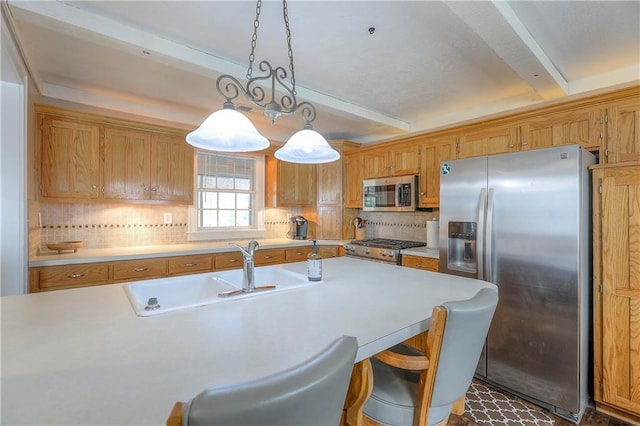 kitchen featuring stainless steel appliances, light countertops, a sink, and decorative backsplash