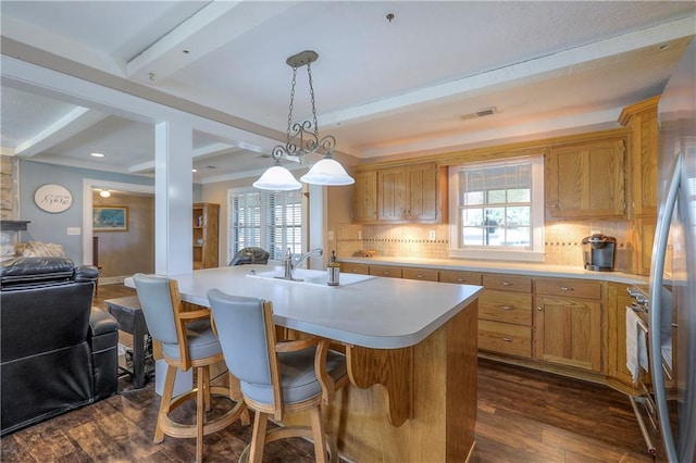 kitchen with dark wood-style flooring, beamed ceiling, light countertops, and a wealth of natural light
