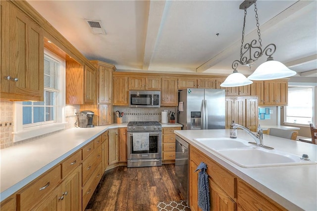 kitchen featuring light countertops, a sink, hanging light fixtures, stainless steel appliances, and beam ceiling