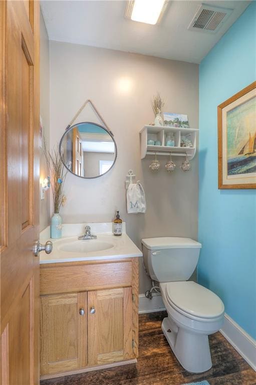 bathroom with toilet, vanity, baseboards, and visible vents