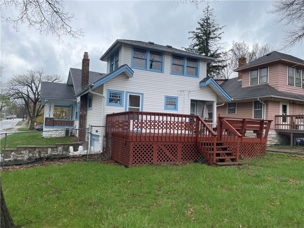 rear view of property with a lawn, fence, a wooden deck, and a chimney