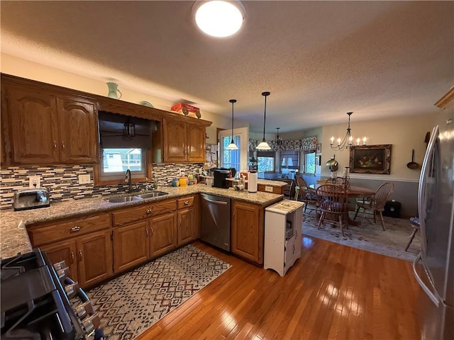 1200 Susan St, Kearney, MO 64060 - kitchen featuring a sink, appliances with stainless steel finishes, a peninsula, light wood-type flooring, and a chandelier