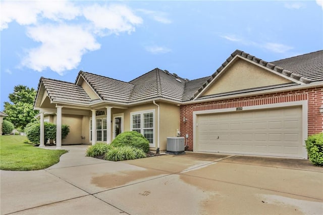 5428 W 145th Ter, Leawood, KS 66224 - view of front facade with central air condition unit, stucco siding, a tiled roof, a garage, and concrete driveway
