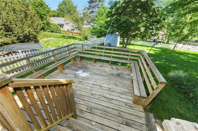 wooden terrace with a storage shed, an outbuilding, and a trampoline