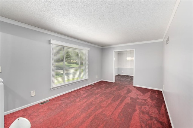 empty room with a textured ceiling, carpet floors, ornamental molding, baseboards, and a chandelier