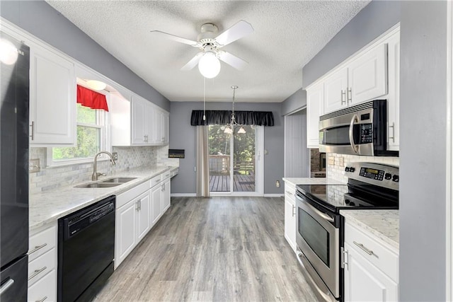 kitchen with black appliances, a sink, white cabinetry, healthy amount of natural light, and a textured ceiling
