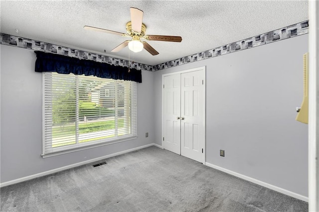unfurnished bedroom with carpet, baseboards, a textured ceiling, a closet, and ceiling fan