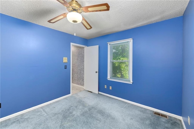 empty room featuring ceiling fan, a textured ceiling, carpet, and baseboards