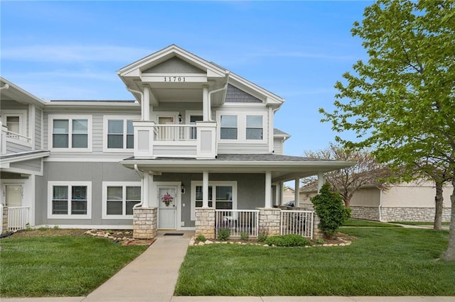 view of front facade with a porch, stucco siding, stone siding, and a front yard