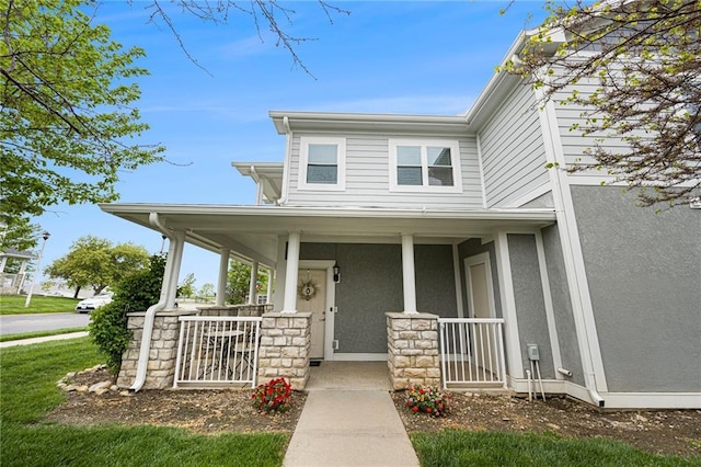 view of front of property featuring covered porch, stucco siding, and stone siding