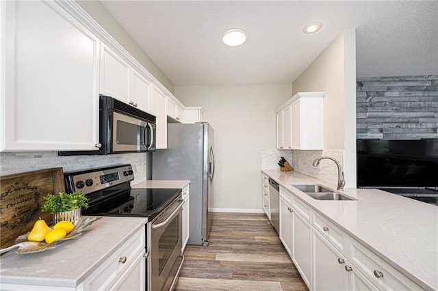 kitchen featuring decorative backsplash, appliances with stainless steel finishes, light wood-type flooring, a sink, and white cabinets
