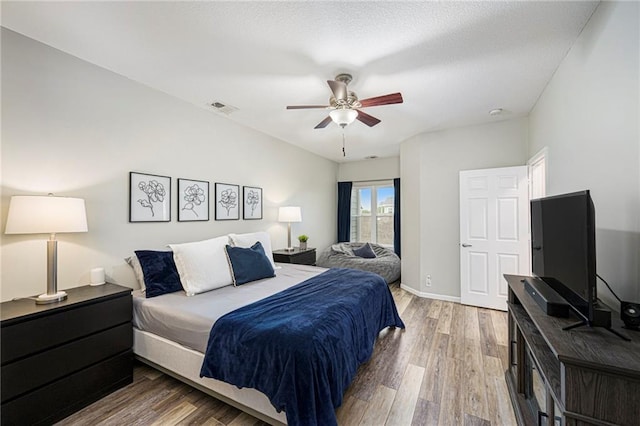 bedroom featuring baseboards, a ceiling fan, light wood-style flooring, and visible vents