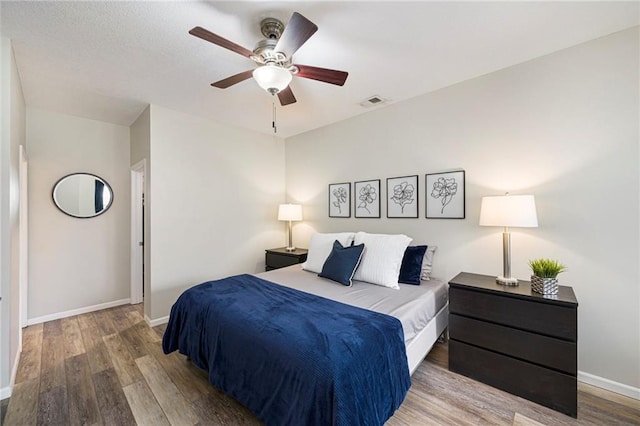 bedroom with baseboards, ceiling fan, wood finished floors, and visible vents