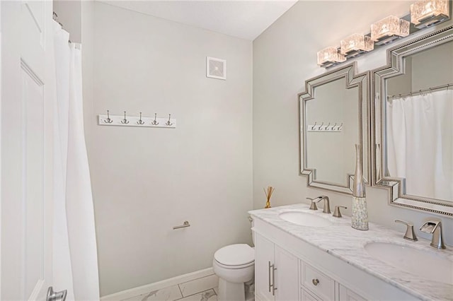 bathroom featuring toilet, baseboards, a sink, and marble finish floor