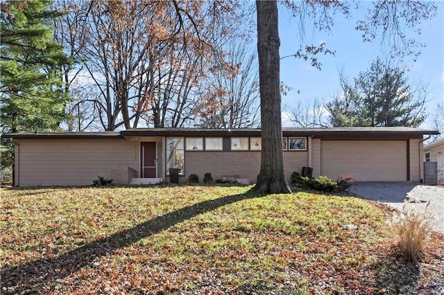view of front of property with a garage, driveway, a front lawn, and brick siding