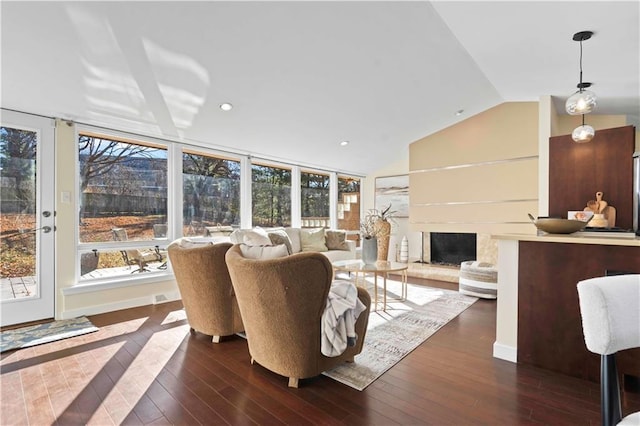 living room featuring dark wood-style flooring, a fireplace with raised hearth, vaulted ceiling, and recessed lighting