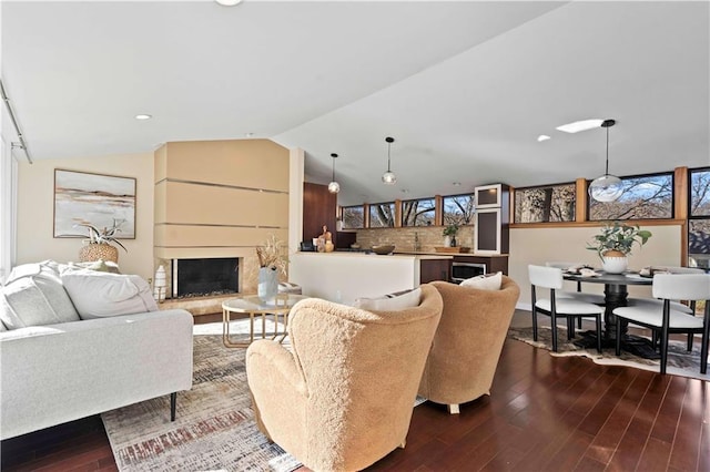 living room featuring dark wood finished floors, recessed lighting, a fireplace with raised hearth, and lofted ceiling