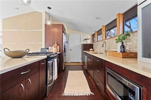 kitchen with light countertops, appliances with stainless steel finishes, a sink, and vaulted ceiling