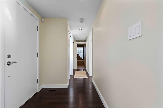 hallway with dark wood-type flooring, baseboards, visible vents, and recessed lighting