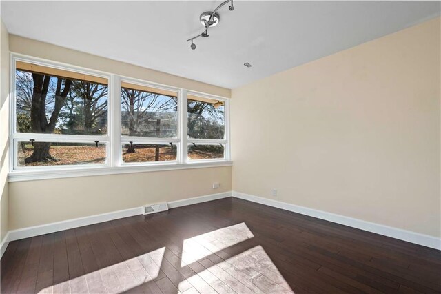 unfurnished room with track lighting, hardwood / wood-style floors, visible vents, and a wealth of natural light