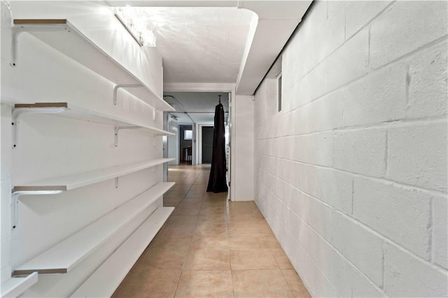corridor featuring light tile patterned floors and concrete block wall