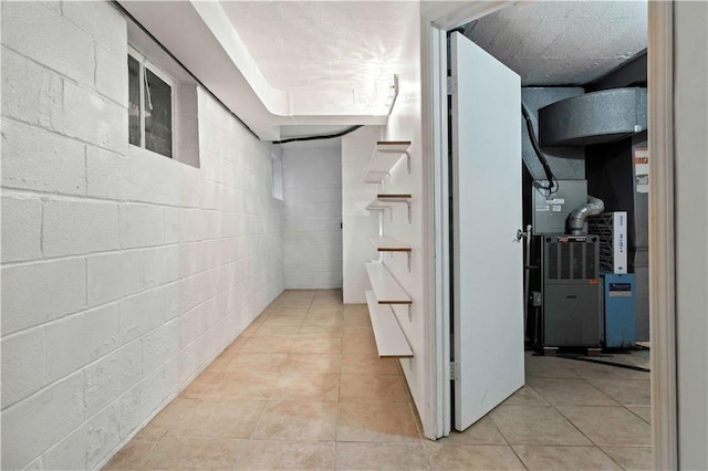 corridor featuring light tile patterned flooring and concrete block wall