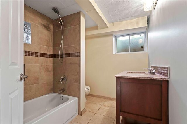 bathroom featuring baseboards, shower / washtub combination, toilet, vanity, and tile patterned flooring