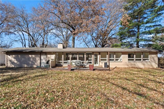 rear view of house with a yard, a sunroom, a patio area, and a chimney