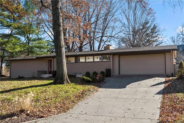 view of front of property featuring concrete driveway, a chimney, a front lawn, brick siding, and a garage