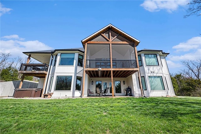 back of property featuring a hot tub, a lawn, a sunroom, and a patio area