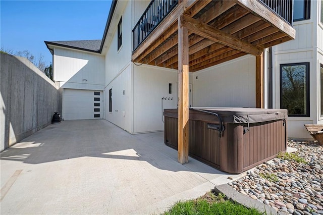 view of patio featuring a garage, a hot tub, and concrete driveway