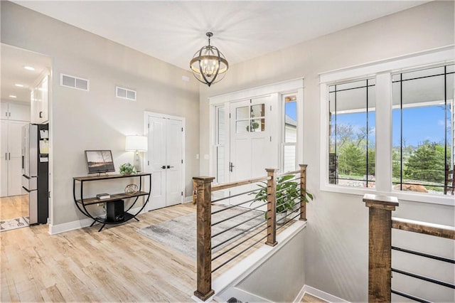 entryway with visible vents, light wood-style flooring, baseboards, and a chandelier