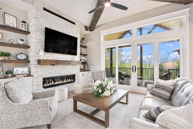 living room featuring french doors, vaulted ceiling with beams, a ceiling fan, and a stone fireplace